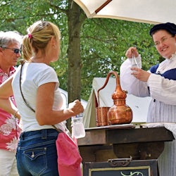 Man and woman at booth with reenactor demonstrating a craft