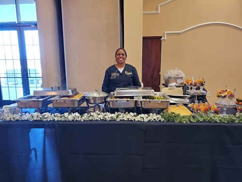 Crystal standing behind table of food by Crystals Catering and Sweet Treats